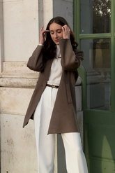 a lady in a white top, a brown coat and a pair of white wide leg pants